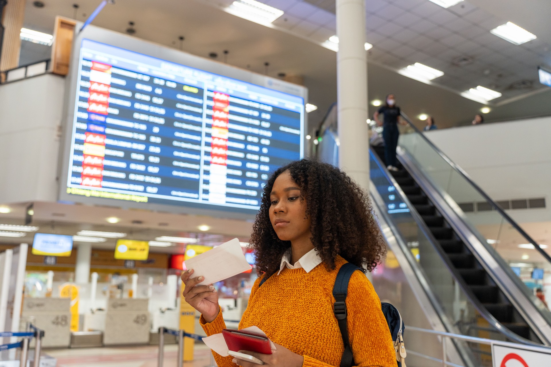 Black women is looking to check flight number, boarding time and gate number to board a flight to travel.